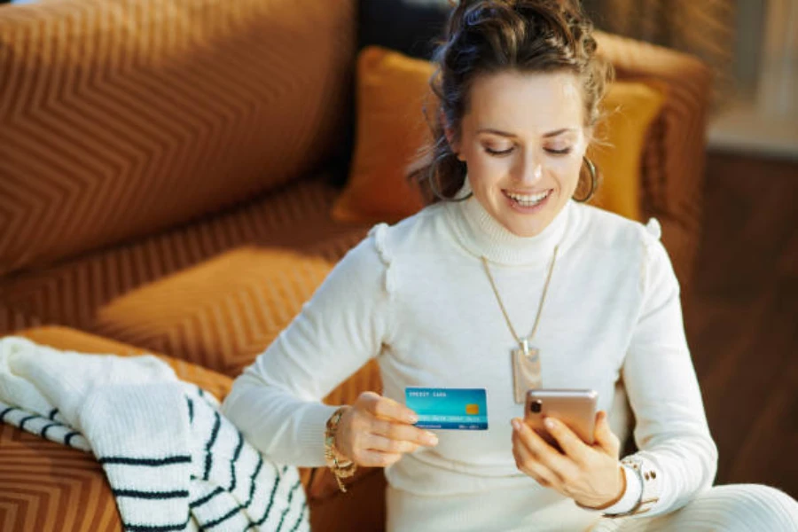 Happy trendy woman making a payment at a fashion online shop
