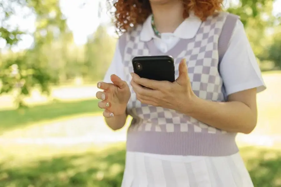 Señora sosteniendo un teléfono con un traje de color neutro