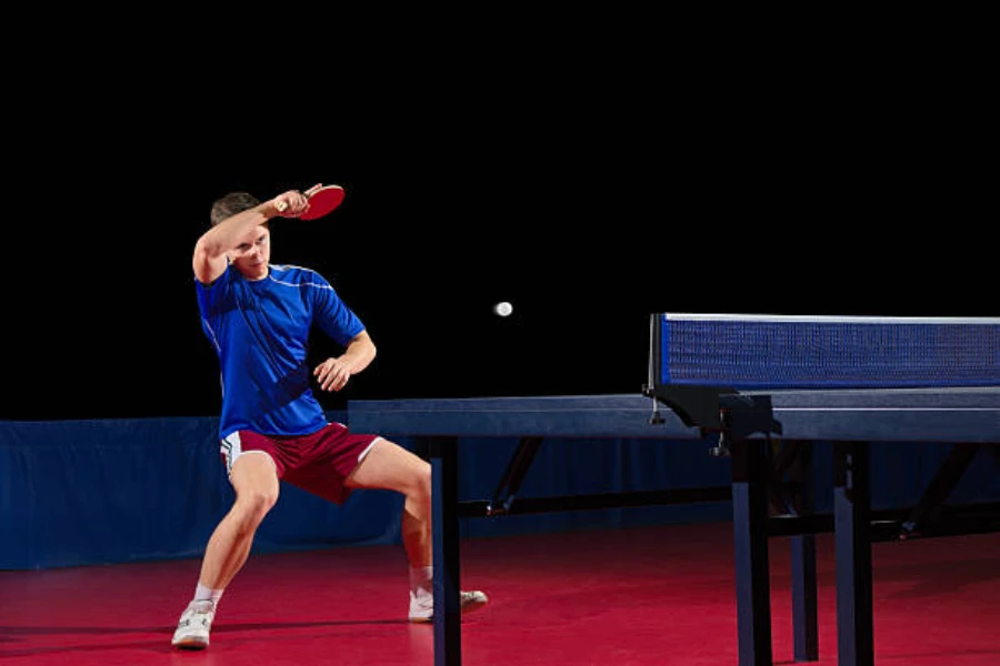 Man wearing unisex table tennis shoes on a red court
