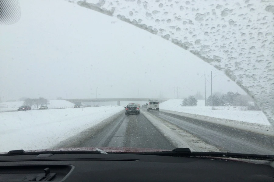 Blick auf die verschneite Straße von der Windschutzscheibe eines Autos aus