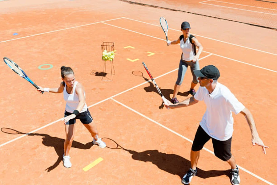 Two women with tennis coach using tennis training equipment