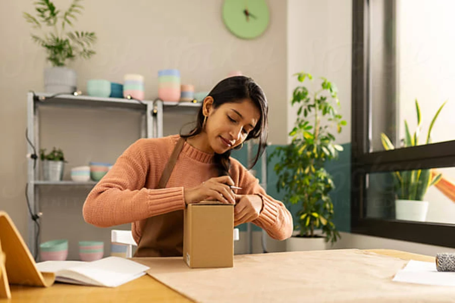 Woman at her desk office preparing a box for shipping