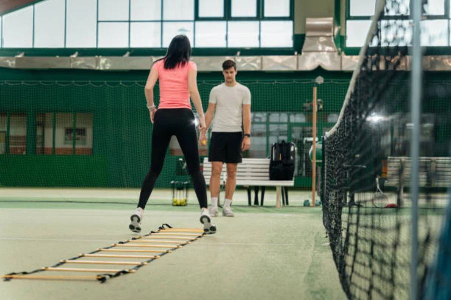 Woman using agility ladder on an indoor tennis court