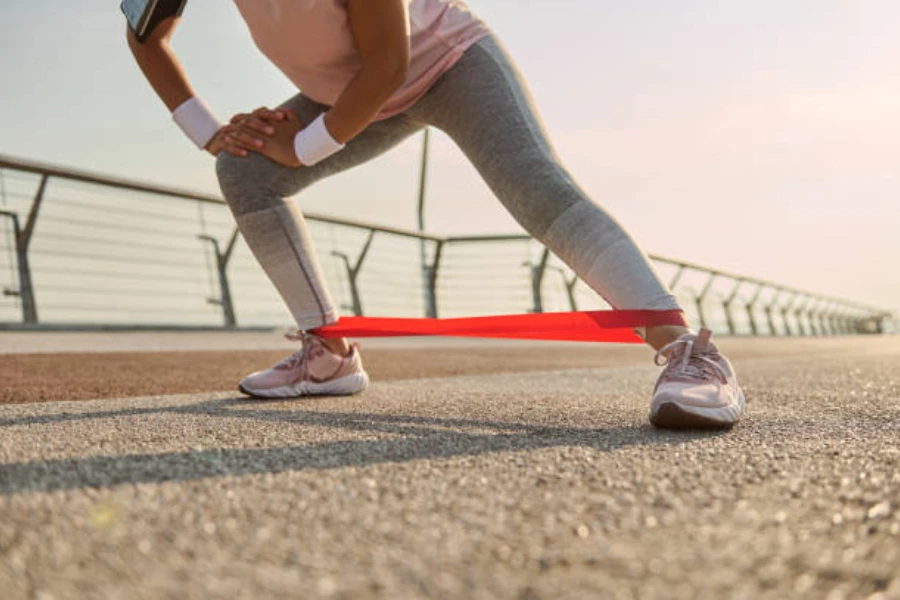 Woman warming up legs using a red resistance band