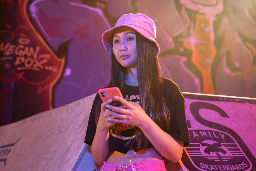 Mujer con un sombrero de cubo rosa y sosteniendo su teléfono