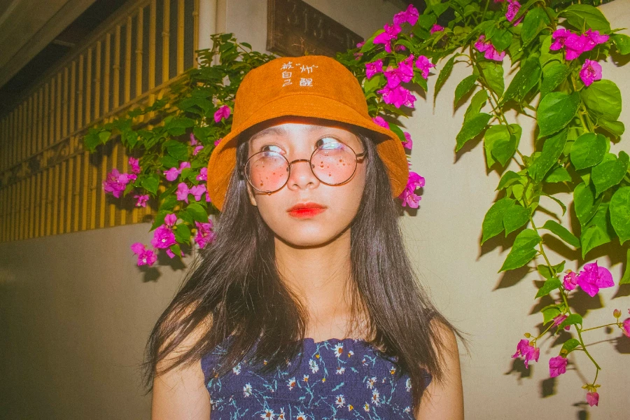 Woman wearing an orange bucket hat and blue floral shirt