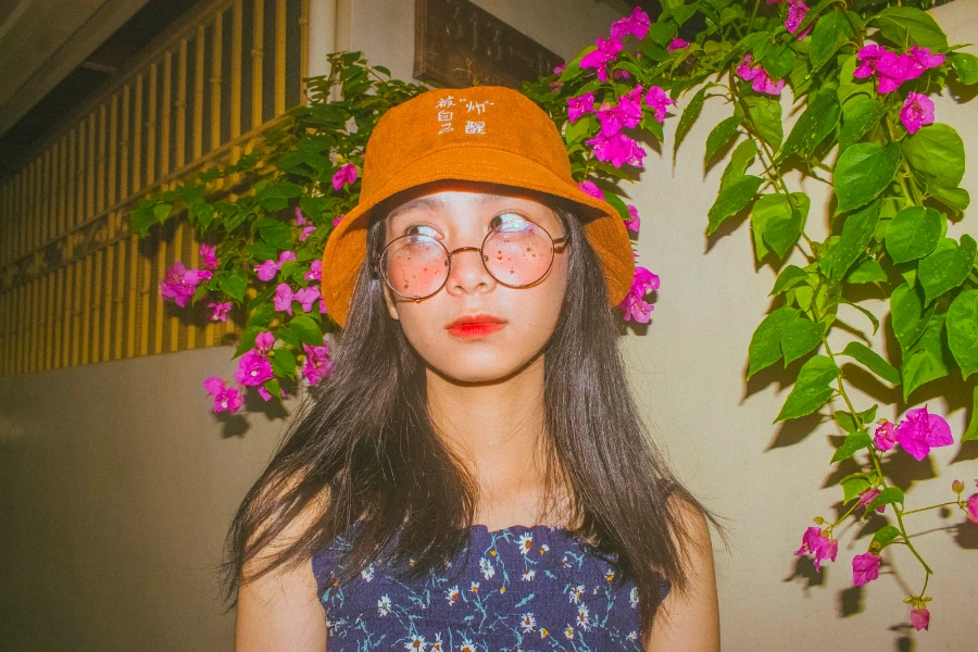 Femme portant un bob orange et une chemise à fleurs bleues